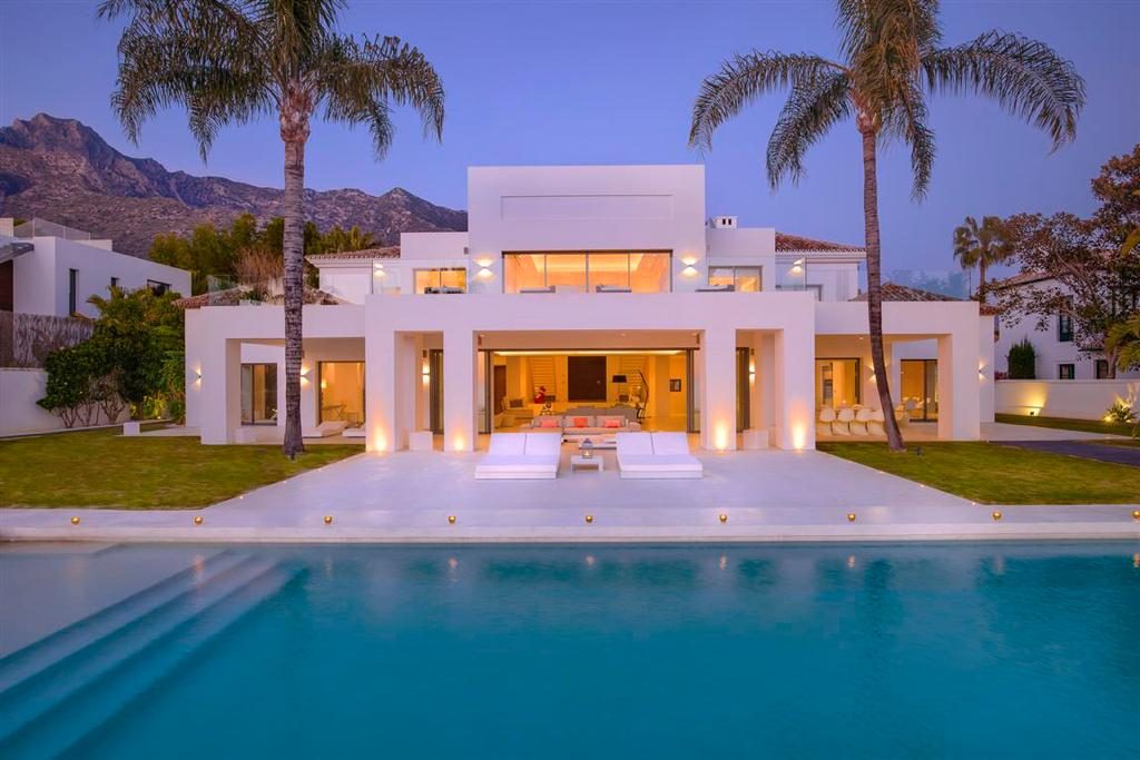 Luxury white and big villa with pool and palms behinds.
